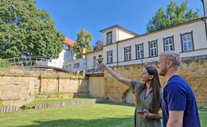 Zwei Teilnehmende stehen im grünen Außenbereich einer historischen Anlage in Peine und orientieren sich während einer digitalen Stadtrallye.