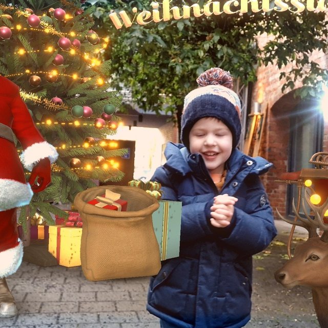 Augmented-Reality-Szene mit weihnachtlichem Motiv: In einer realen, städtischen Umgebung wird eine virtuelle Weihnachtswelt eingeblendet. Zu sehen sind eine digital dargestellte Figur des Weihnachtsmanns, ein geschmückter Weihnachtsbaum mit Lichtern und Geschenken sowie ein Rentier mit beleuchtetem Schlitten. Davor steht ein Kind in winterlicher Kleidung, das mit den virtuellen Elementen interagiert. Reale Architektur und Pflanzen bilden den Hintergrund und machen die Kombination aus digitaler Darstellung und realem Raum deutlich sichtbar.