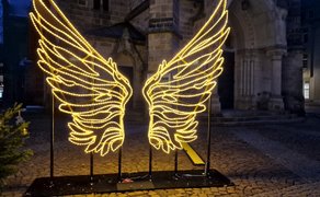 Leuchtende Engelsflügel als Lichtskulptur vor der St.-Jacobi-Kirche auf dem Marktplatz in Peine, Niedersachsen, bei Nacht mit historischer Architektur und stimmungsvoller Innenstadtatmosphäre.