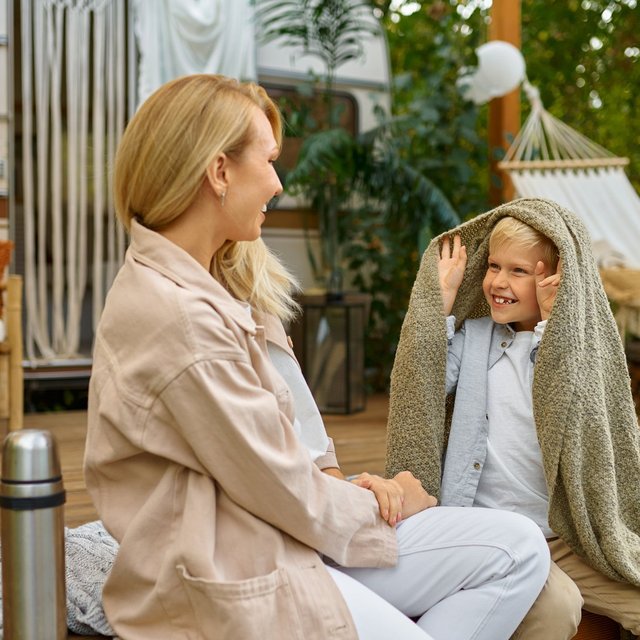 Mutter und Kind sitzen vor einem Wohnmobil und genießen gemeinsam eine entspannte Campingzeit im Grünen bei Peine.
