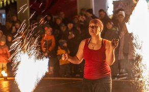 Das Bild zeigt eine Frau während der Feuershow. Es sprühen Funken. 