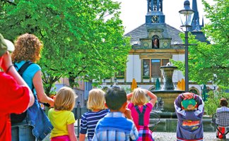 Das Bild zeigt eine Gruppe Kinder, die an einer Kinderstadtführung in Peine teilnehmen und sich das Alte rathaus am Historischen Marktplatz anschauen. 