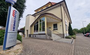 Eingang eines Hauses aus der Froschperspektive sowie ein Schild mit der Aufschrift „Peiner Heimstätte“.