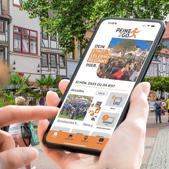Person nutzt die Peine2Go-App auf dem Smartphone in der Peiner Innenstadt, um digitale Angebote, Informationen und Stadterlebnisse mobil zu entdecken.
