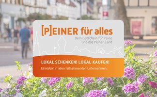 Das Bild zeigt im Fokus den Stadtgutschein Peiner für alles und dahinter die belebte Peiner Innenstadt.