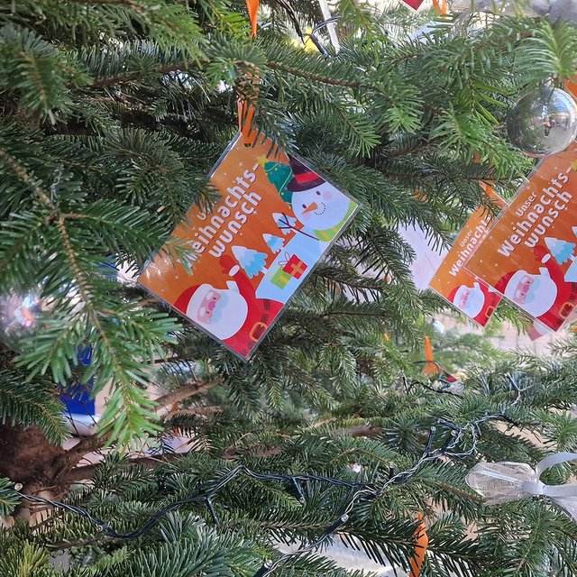 Tannenzweige mit mehreren bunten Wunschkarten, darauf Weihnachtsmann, Geschenke und der Text 'Weihnachts Wunsch'.