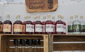 Regal mit Flaschen verschiedener Spirituosen, darunter Rum, Sloe Gin und Gin, auf einem Marktstand