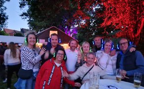 Das Bild zeigt eine Gruppe Menschen die bei der Silent Music Party im Burgpark Peine feiern. 