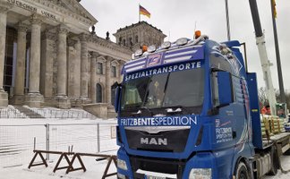 Blauer Spezialtransport-Lkw der Firma Fritz Bente Spedition vor dem Reichstagsgebäude in Berlin.