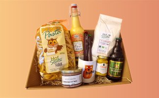 Geschenkkorb mit Pasta, Eierlikör, Aufstrichen in Glasdosen, Dose, Tasse und Bierflasche auf Holzwolle in Karton