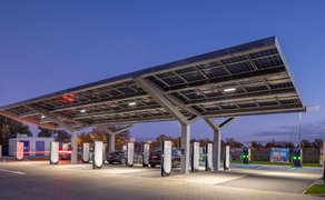 Unter einem großen Carportdach mit Solarzellen sind etwa ein Dutzend Parkplätze mit Ladesäulen zu sehen. 
