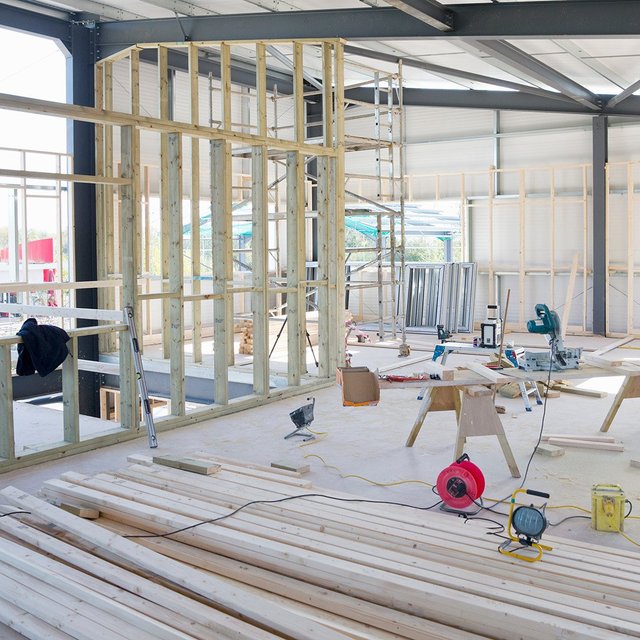Umbau in einer Halle mit Holzständerwänden, Gerüst und Baumaterialien mit der KfW-Förderung Gewerbe zu Wohnen.