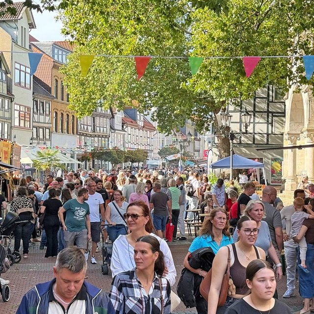 „Belebte Fußgängerzone in einer deutschen Innenstadt mit zahlreichen Passanten, Außengastronomie, Geschäften und begrünten Bereichen.“