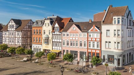 Bunte historische Häuserfassaden am Marktplatz in Peine mit Fachwerk, kleinen Bäumen und gemütlicher Innenstadtatmosphäre.