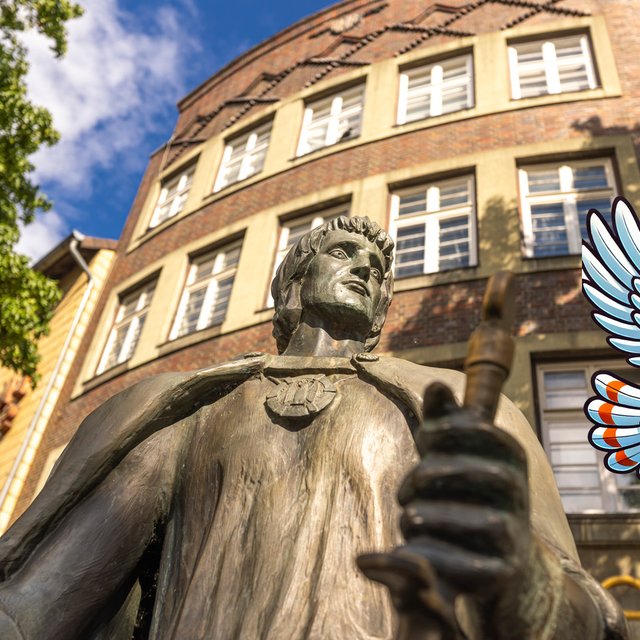 Das Peiner Maskottchen Uhlinchen fliegt über die Statue des Grafen Gunzelin. 