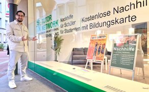 Ein Mann in weißer Kleidung steht vor einem Schaufenster mit der Aufschrift „Tutor Network“, hinter der Scheibe sind zwei Aufsteller mit Informationsplakaten zum Peiner Förderprojekt "GetStarted" und Nachhilfe zu sehen. 