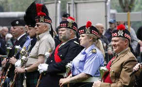 Feierliche Siegerehrung beim Highland Gathering: Teilnehmer in traditionellen schottischen Uniformen mit Tartan-Bonnets und roten Federn stehen nebeneinander und halten silberne Pokale – würdevoller Moment eines schottischen Kultur- und Sportevents.