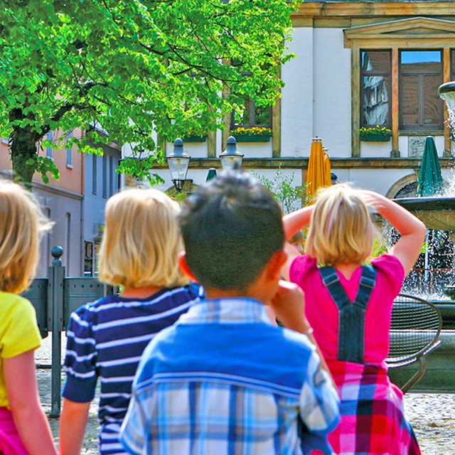 Das Bild zeigt eine Gruppe von Kindern, die gerade das alte Rathaus in Peine bei einer Kinderstadtführung bestaunen. 