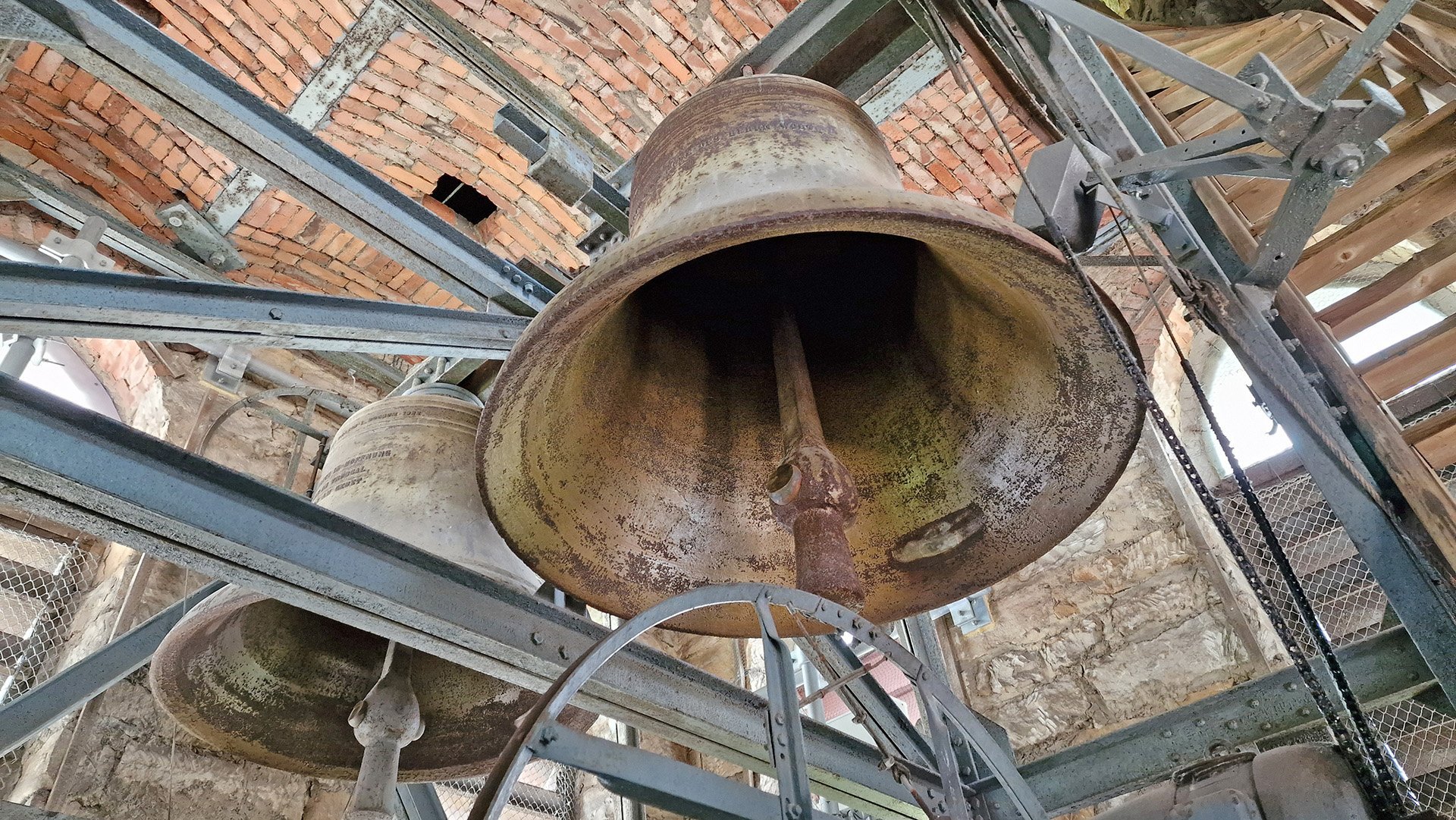Zwei Glocken der St.-Jakobi-Kirche Peine sind von unten zwischen Stahlträgern und gemauerten Wänden zu sehen.