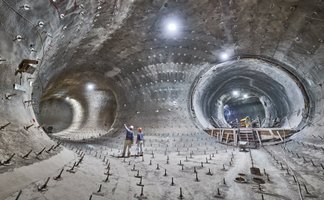 Das Bild zeigt Bergbauleute unter Tage in einer zum Teil bereits mit Beton verschalten Strecke.