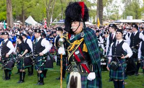 Anführer in traditioneller schottischer Uniform mit Federhut steht vor Pipe Band beim Highland Gathering im Peiner Stadtpark vor großem Publikum