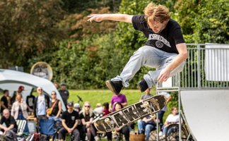 Skateboarder führt einen Sprung im Skaterpark in Peine aus, während Zuschauer das Event verfolgen.