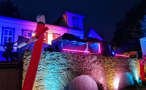 Open-Air-Event im Peiner Burgpark bei Nacht: farbig illuminierte historische Fassade, DJ unter beleuchtetem Zelt, tanzende Besucher und rote LED-Lichtinstallationen bei der Silent Music Party in Peine.