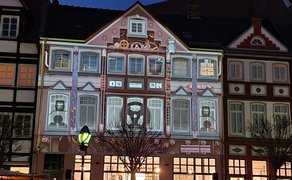 Videomapping-Projektion verwandelt eine historische Hausfassade in der Peiner Innenstadt in eine animierte Lichtinstallation mit Motiven aus Industrie- und Stadtgeschichte.