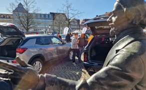 Autoausstellung beim BraWo Mobility Spring in der Innenstadt Peine mit geöffneten Kofferräumen, Besuchern und historischer Statue im Vordergrund.