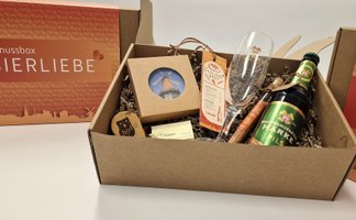 Geschenkbox „Bierliebe“ aus Peine mit einer Flasche Härke Pils, Bierglas, kleinen regionalen Produkten und dekorativer Verpackung auf einem Tisch.