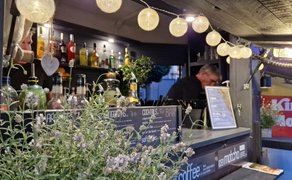 Stimmungsvolle Cocktail- und Getränkebar beim Peiner Weinfest mit beleuchteter Theke, Spirituosenflaschen, Kräuterdekoration und Barkeeper im Hintergrund.