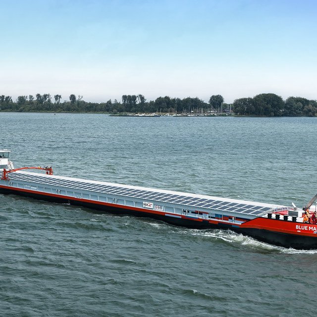 Das Bild zeigt ein fahrendes Binnenschiff mit Solarzellen auf der Abdeckung des Frachtraums.