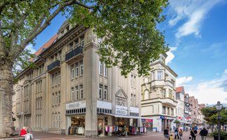 Historisches Geschäftsgebäude in der Peiner Innenstadt mit klassischer Fassade und Einzelhandel – Architektur in Peine unter blauem Himmel.