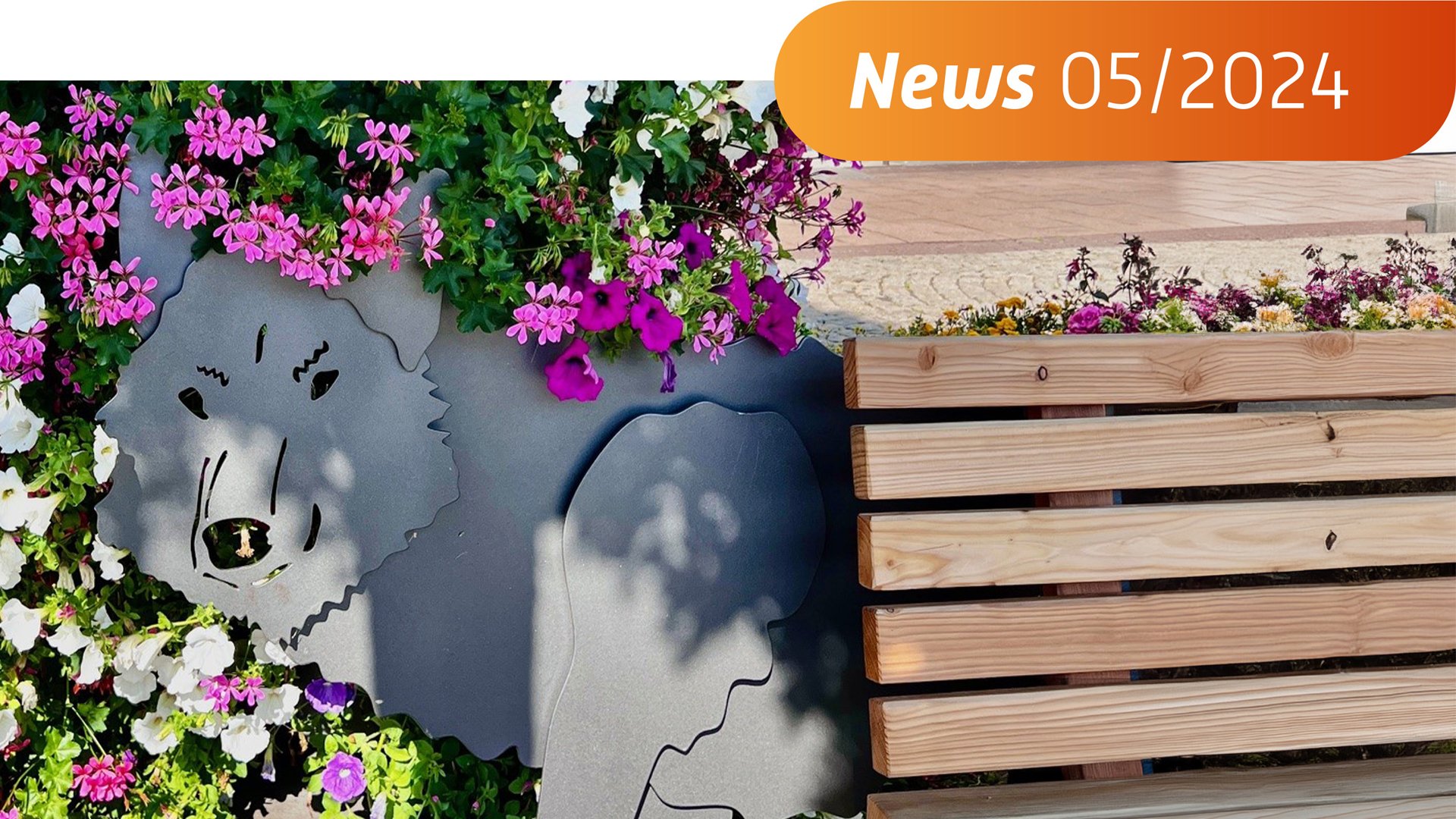 Das Bild zeigt eine Bank mit einem stilisierten Wolf dahinter und bunten Blumen. 