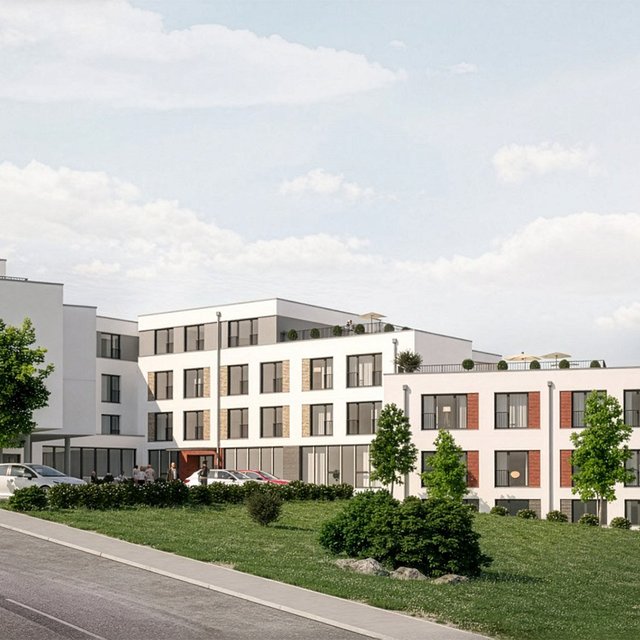 Mehrstöckiges modernes Gebäude mit großen Fenstern und Bäumen auf einem leicht ansteigenden Gelände.