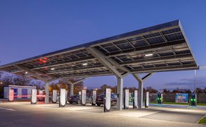 Das Bild zeigt eine Außenaufnahme des Schokoladenhaus Rausch in Peine, auf dem die Tesla-Ladestationen zu sehen sind.. 