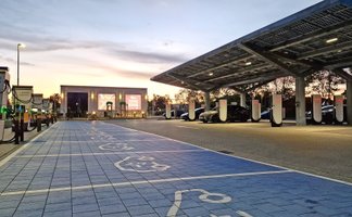 Das Bild zeigt eine Reihe von Parkplätzen mit Ladesäulen sowie ein Carport mit Solarzellen. 