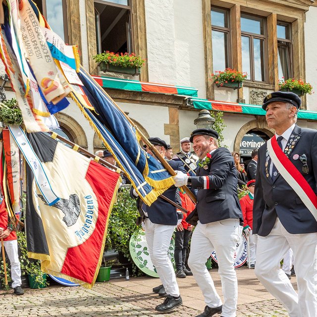 Fahnenträger in historischen Uniformen ziehen während des Peiner Freischießens über den Marktplatz.