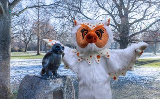 Uhlinchen als Maskottchen des Peiner Stadtmarketings im Stadtpark neben der Eulenskulptur, winterliche Szene mit kahlen Bäumen und Parkanlage in Peine