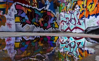 Das Bild zeigt eine Wand, die mit Grafitties besprüht ist.