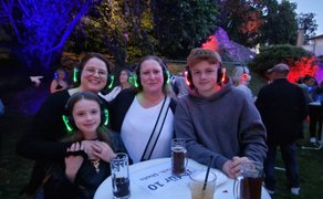 Das Bild zeigt eine Gruppe Menschen die bei der Silent Music Party im Burgpark Peine feiern. 