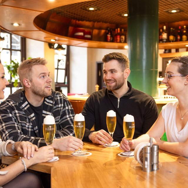 Freunde genießen frisch gezapftes Bier an einem Holztisch in einer gemütlichen Bar in Peine – entspannte Atmosphäre, angeregte Gespräche und moderne Gastronomie im Herzen der Stadt.