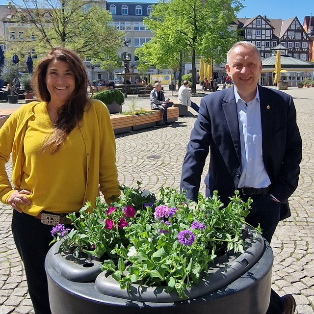 Das Bild zeigt die Geschäftsführerin der Peine Marketing GmbH, Anja Barlen-Herbig, und Peines Bürgermeister Klaus Saemann vor einem neuen Blumenpod in der Peiner Innenstadt. 