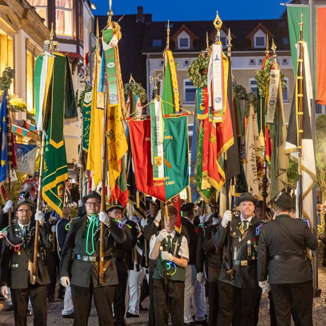 Festumzug beim Peiner Freischießen am Abend, mit Schützen in traditioneller Uniform, Fahnenabordnungen und beleuchteter Innenstadt.