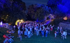 Große Menschenmenge feiert eine Silent Disco im Park bei Nacht, mit leuchtenden Funkkopfhörern, Stehtischen und farbig beleuchteten Bäumen rund um das Veranstaltungsgelände in Peine.
