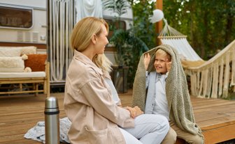 Mutter und Kind sitzen vor einem Wohnmobil und genießen gemeinsam eine entspannte Campingzeit im Grünen bei Peine.