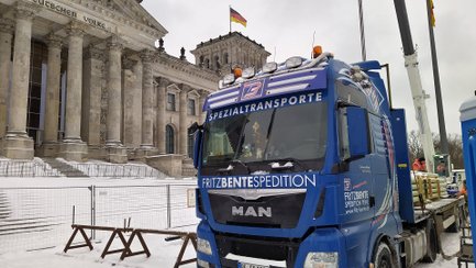 Blauer Spezialtransport-Lkw der Firma Fritz Bente Spedition vor dem Reichstagsgebäude in Berlin.