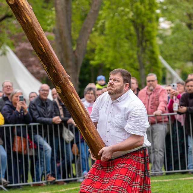 Das Bild zeigt einen Mann der einen Baumstamm wirft, bei den Highland Games, beim Highland Gathering in Peine. 