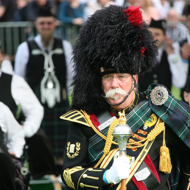 Highland Gathering in Peine mit traditionell gekleidetem Teilnehmer und Dudelsackspielern – Themen-Stadtführung zu internationalen Veranstaltungen in Peine.
