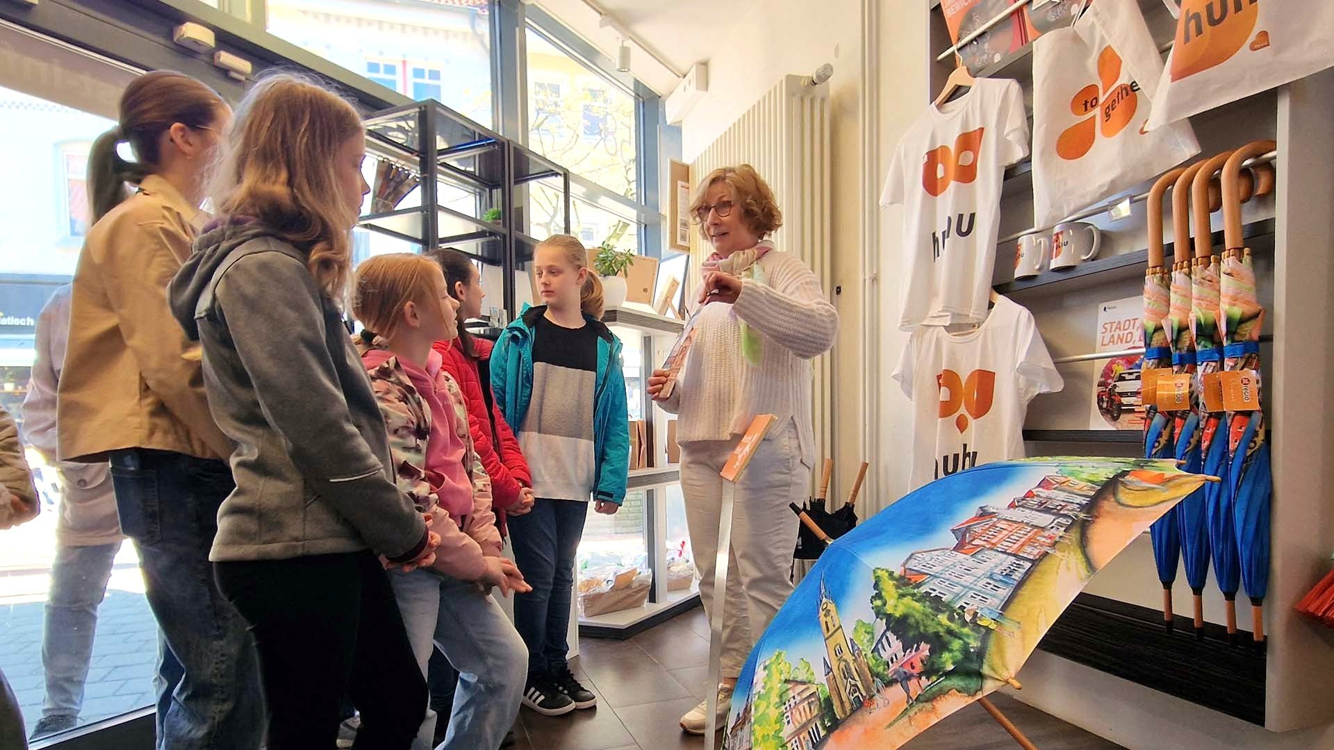 Schülerinnen lassen sich in der Tourist-Information von Peine Marketing das Sortiment des Shops zeigen.